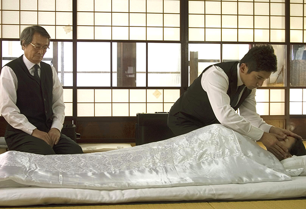 映画『おくりびと』のワンシーン。納棺師が遺体を清めている。