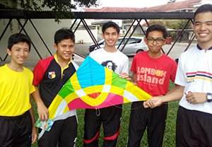 半袖の5人の男性が並んで中央に一つの凧を掲げている。日本文化(凧揚げ)紹介