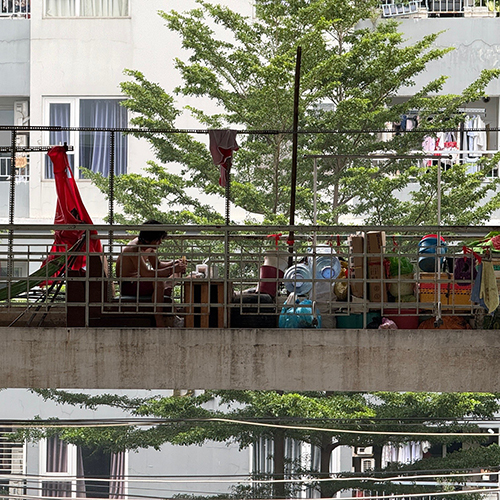 ハンモックやテーブルなど物が広がっているクー・タップ・テーの通路に一人掛けのソファがあり、1人の男性が座っている。