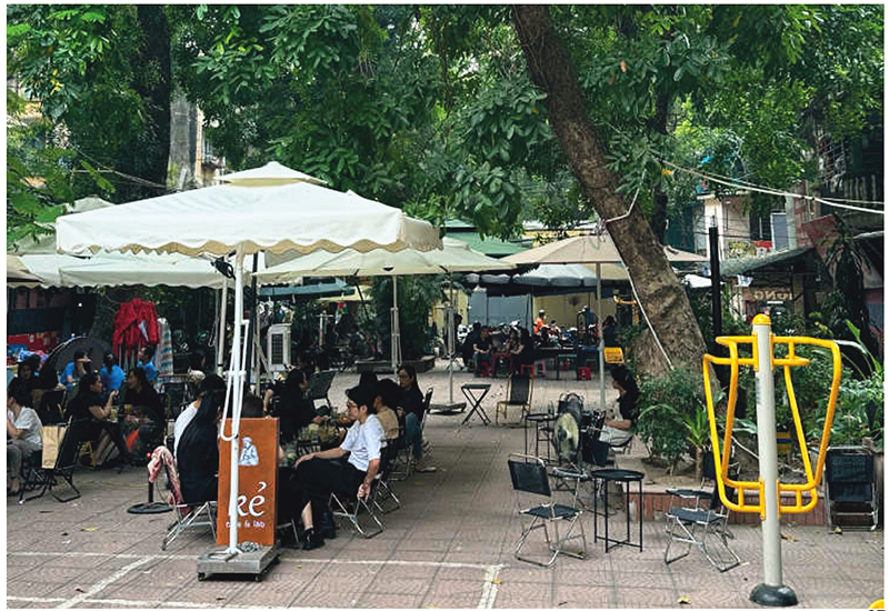 昼間の中庭の風景木々がありパラソルやテントを貼って人々がくつろいでいる