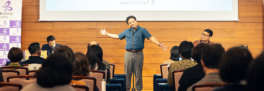 Photo of Paolo reciting a poem and the audience from behind