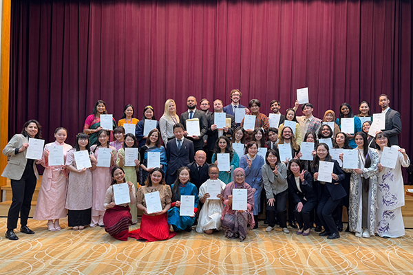 講堂で終了証を手に整列した研修参加者の集合写真